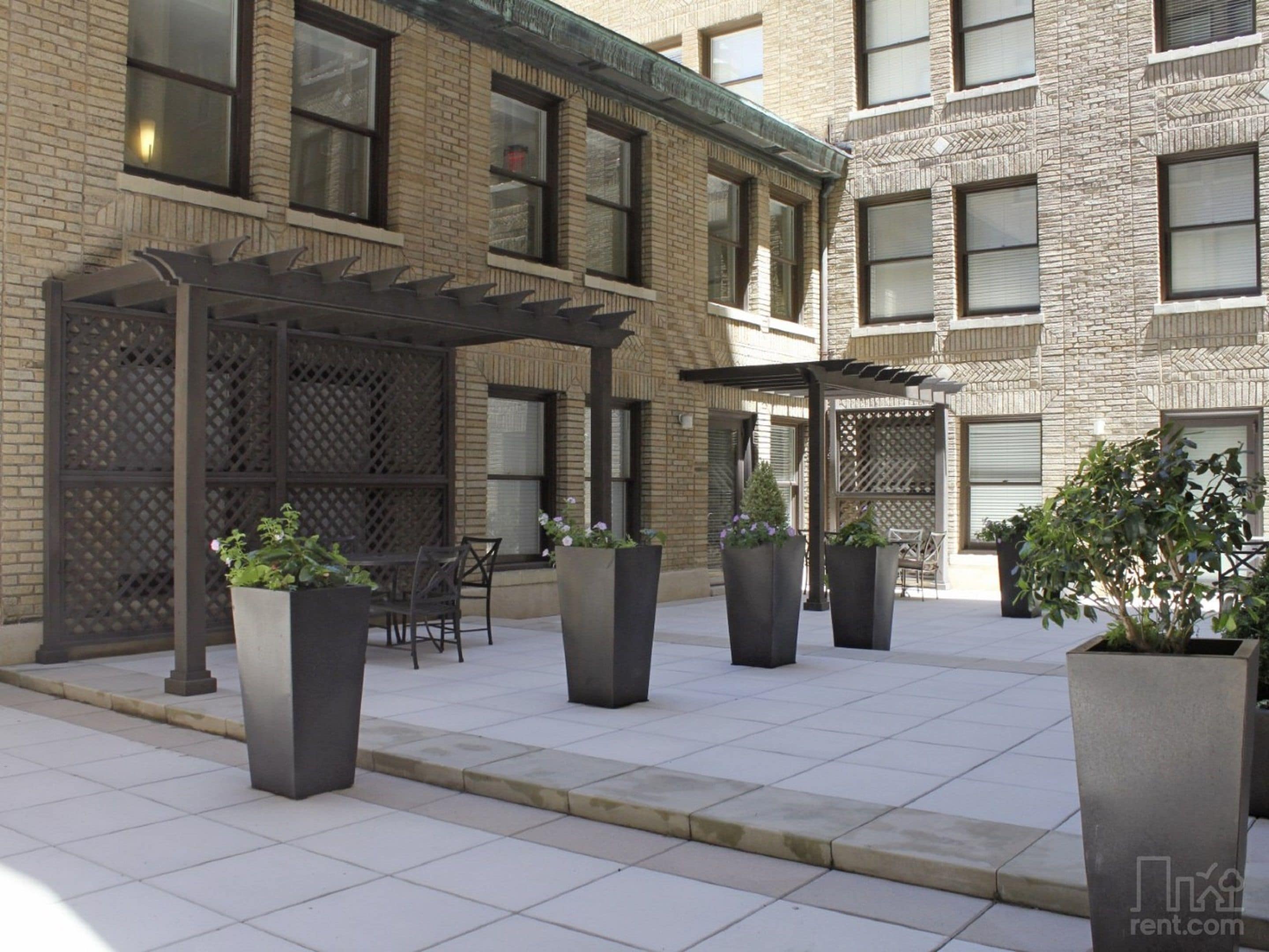 Un espace extérieur aménagé en terrasse, avec une pergola, des sièges et des jardinières.