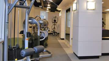 Een sportschool met diverse fitnessapparaten, een spiegelwand en een strak, modern ontwerp.
