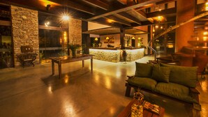A spacious lobby with a stone wall, a reception desk, a green sofa, and a wooden staircase.