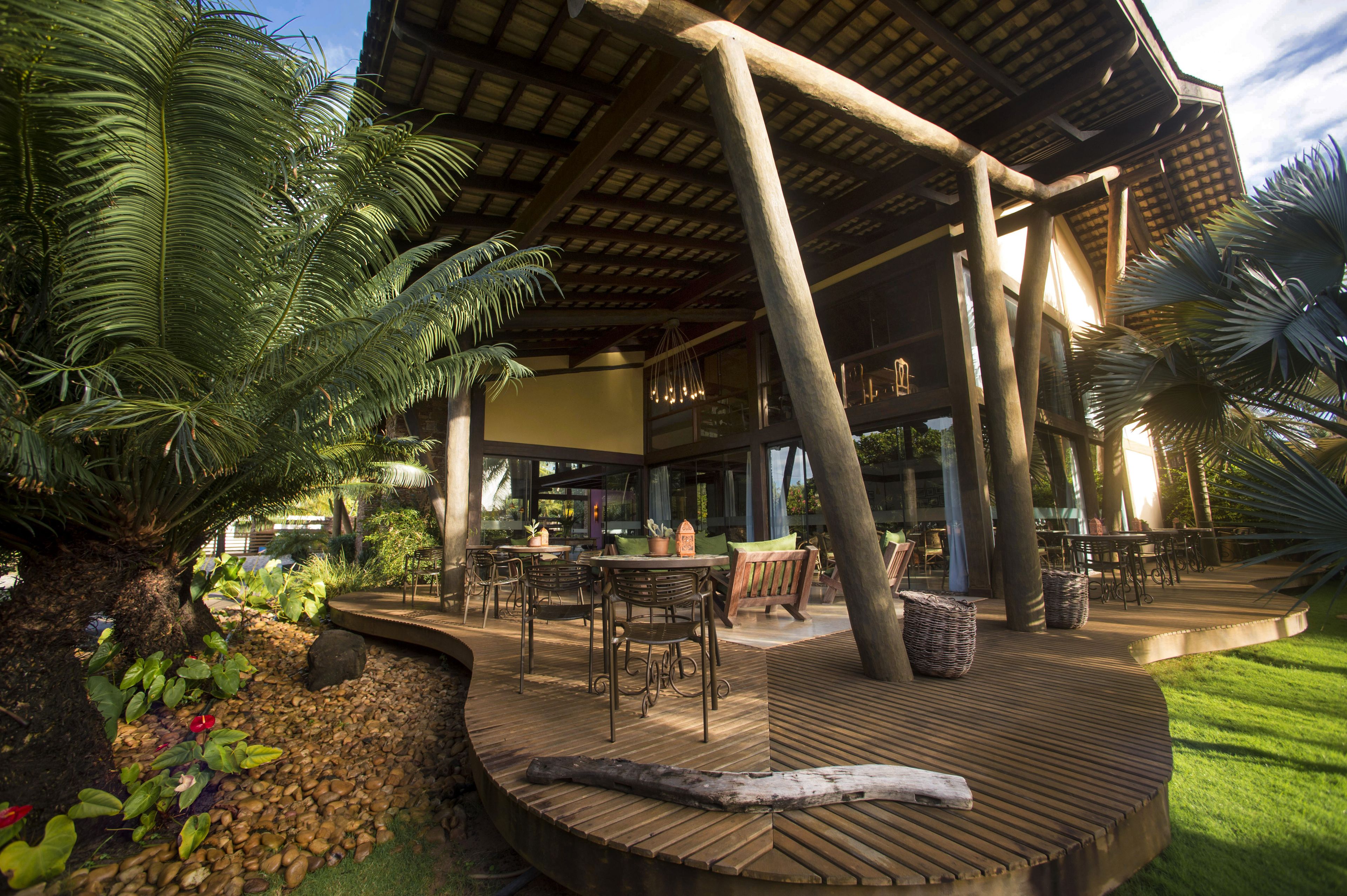 An outdoor patio area with wooden flooring, seating arrangements, and a covered structure.