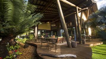An outdoor patio area with wooden flooring, seating arrangements, and a covered structure.