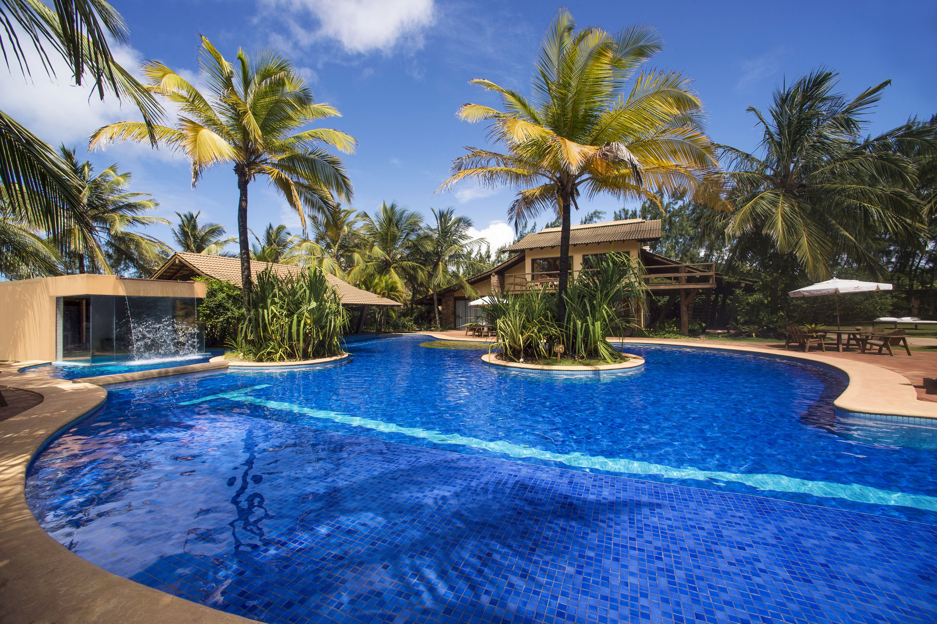 Una piscina al aire libre, sombrillas, sillones reclinables de piscina