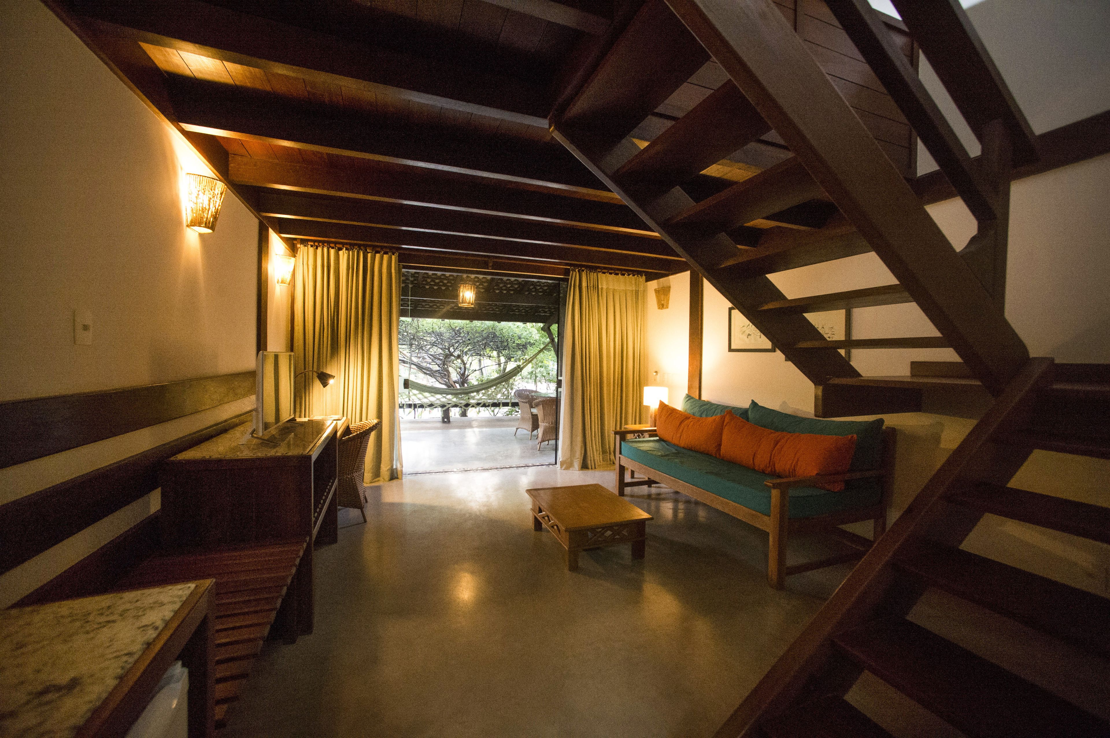 Un interior acogedor con una escalera, un sofá, una mesa de centro y un comedor con banco y mesa.