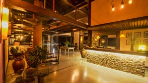 A spacious lobby with a stone wall, wooden beams, and a staircase.