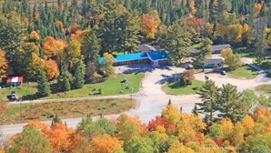 An aerial view of a residential area with houses, a road, and a forested backdrop. - Algonquin Motel (Machar)