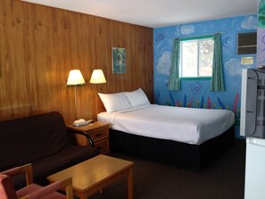 Une chambre d’hôtel avec un mur en bois, un lit avec du linge de maison blanc, un bureau avec une lampe, une télévision et une fenêtre avec des rideaux.