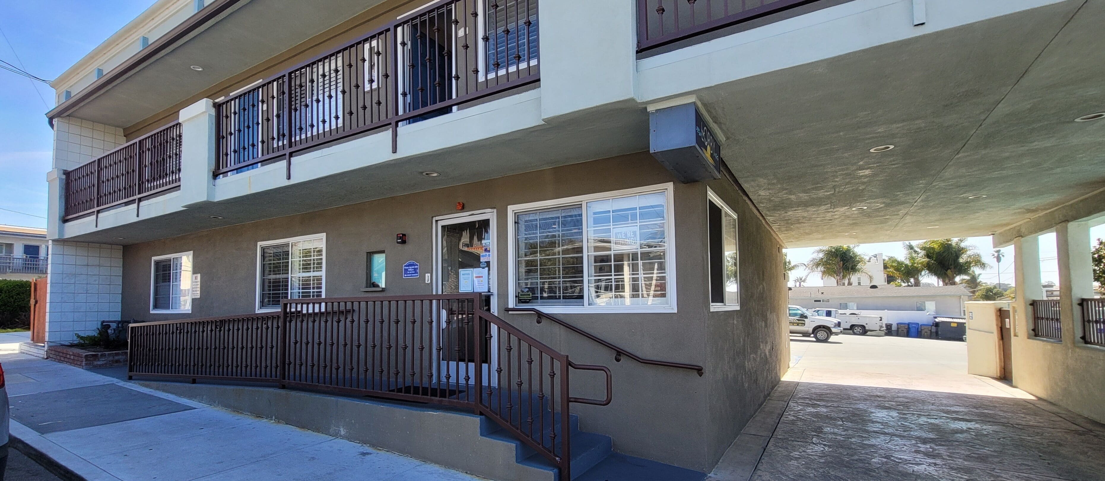 A two-story building with a covered entrance and a staircase leading to the ground floor.