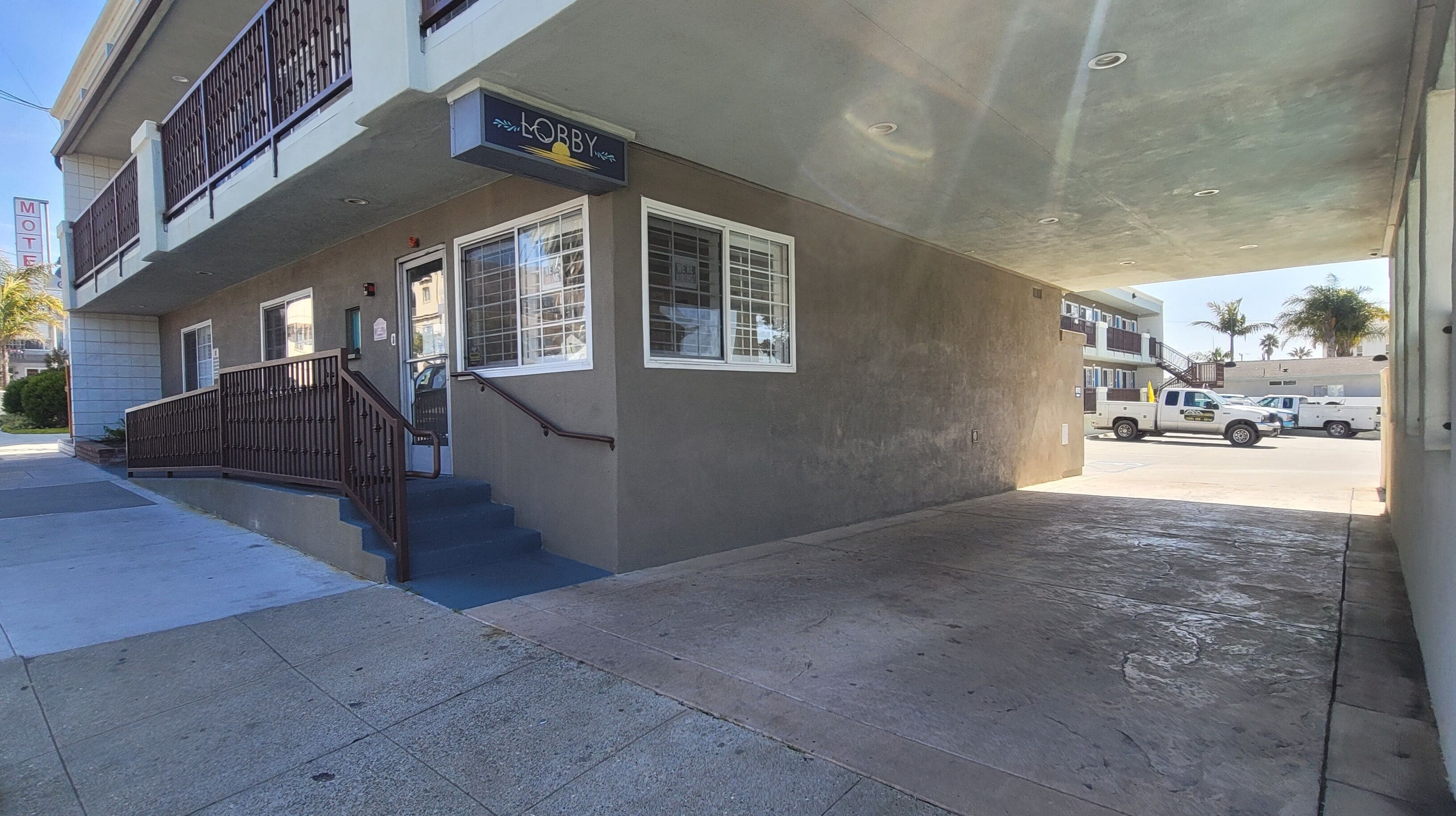 A two-story building with a sign for 'MOBBY' on the ground floor, a staircase leading to the upper floor, and a covered outdoor area with a truck parked nearby.