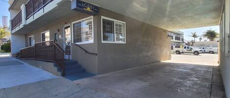A two-story building with a sign for 'MOBBY' on the ground floor, a staircase leading to the upper floor, and a covered outdoor area with a truck parked nearby.