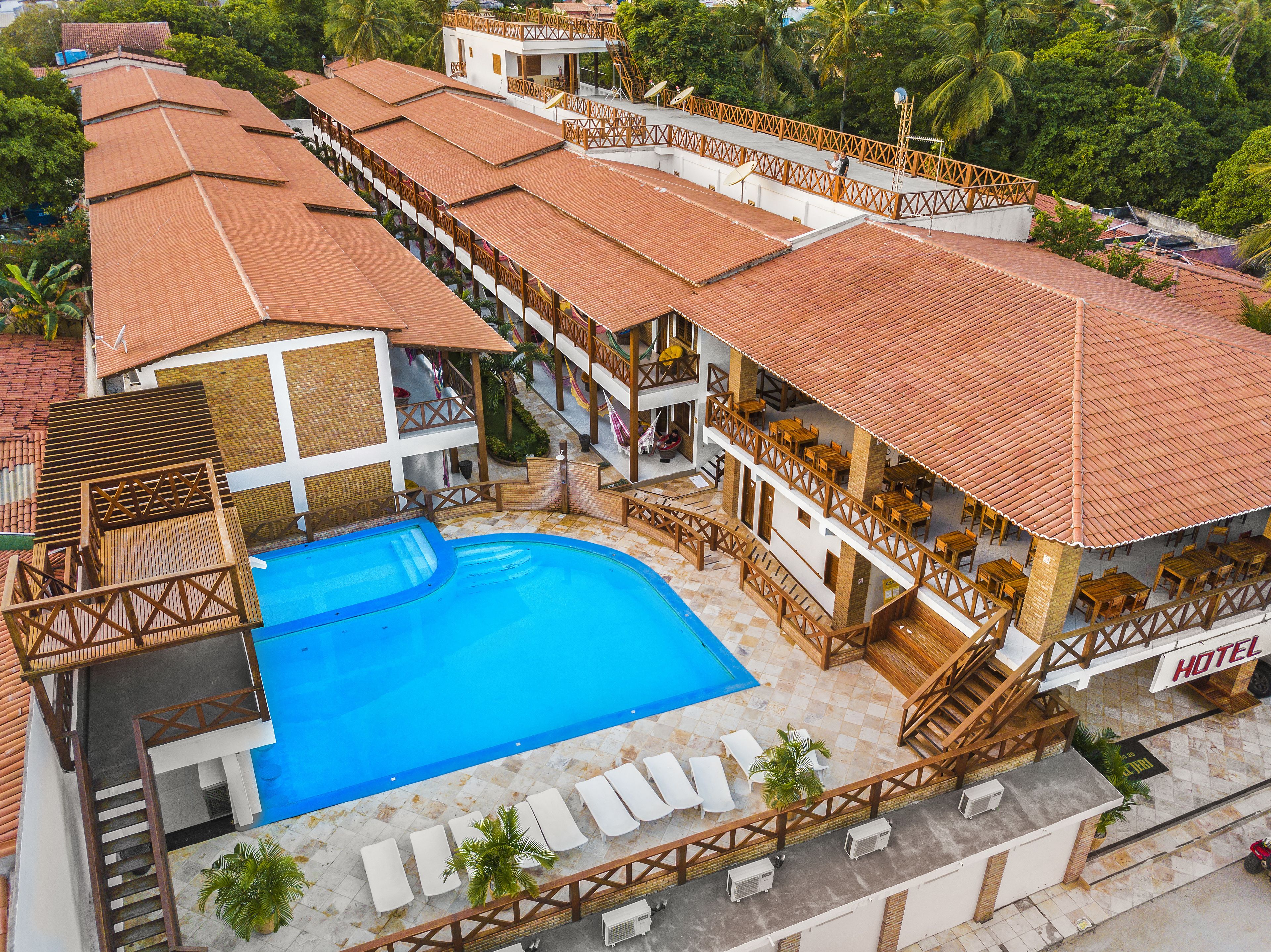 Un hotel con piscina, mobiliario exterior y una zona cubierta con barandillas de madera.