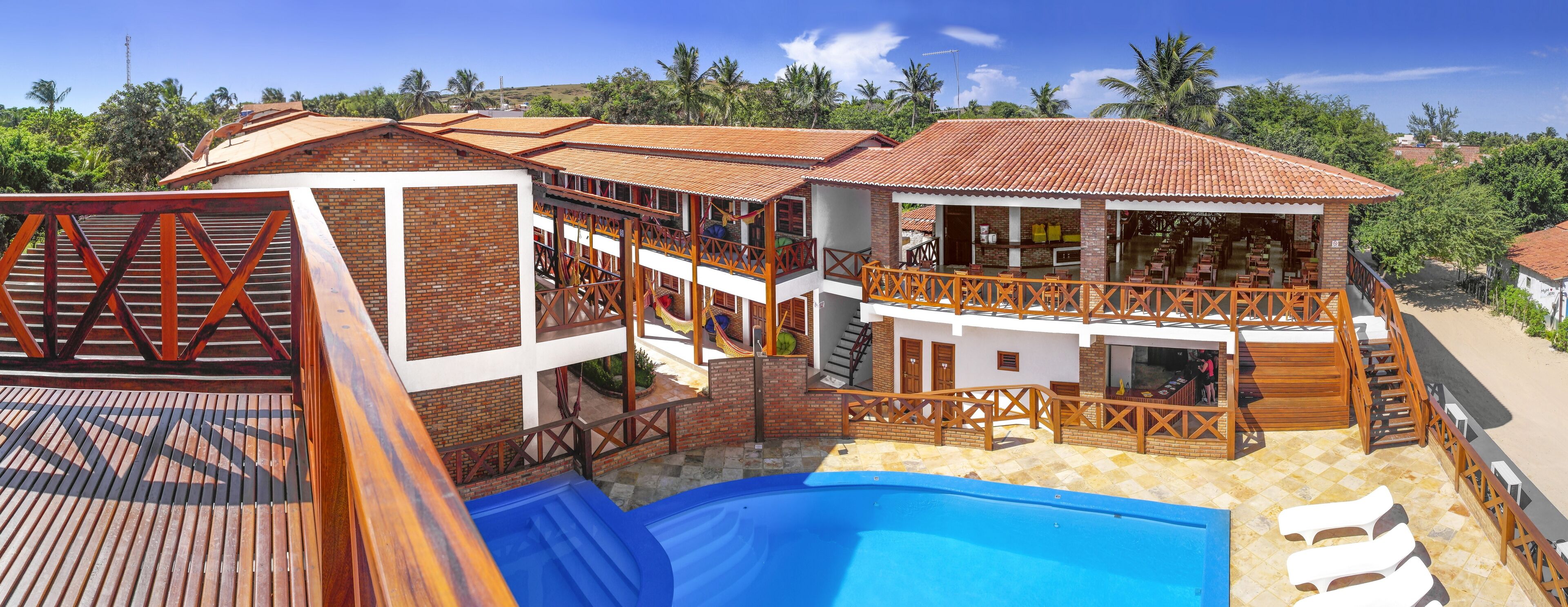 Un edificio de dos pisos con piscina, zona de estar al aire libre y un bar.