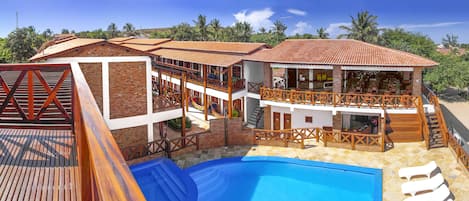 Un edificio de dos pisos con piscina, zona de estar al aire libre y un bar.
