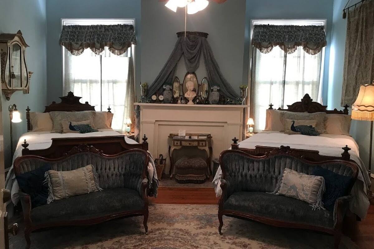 Ein traditionell eingerichtetes Schlafzimmer mit zwei Betten, einem Kamin und einer Kandelaber.