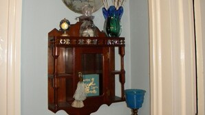 Une vitrine en bois contenant une assiette décorative, un vase bleu et un bol en verre bleu.