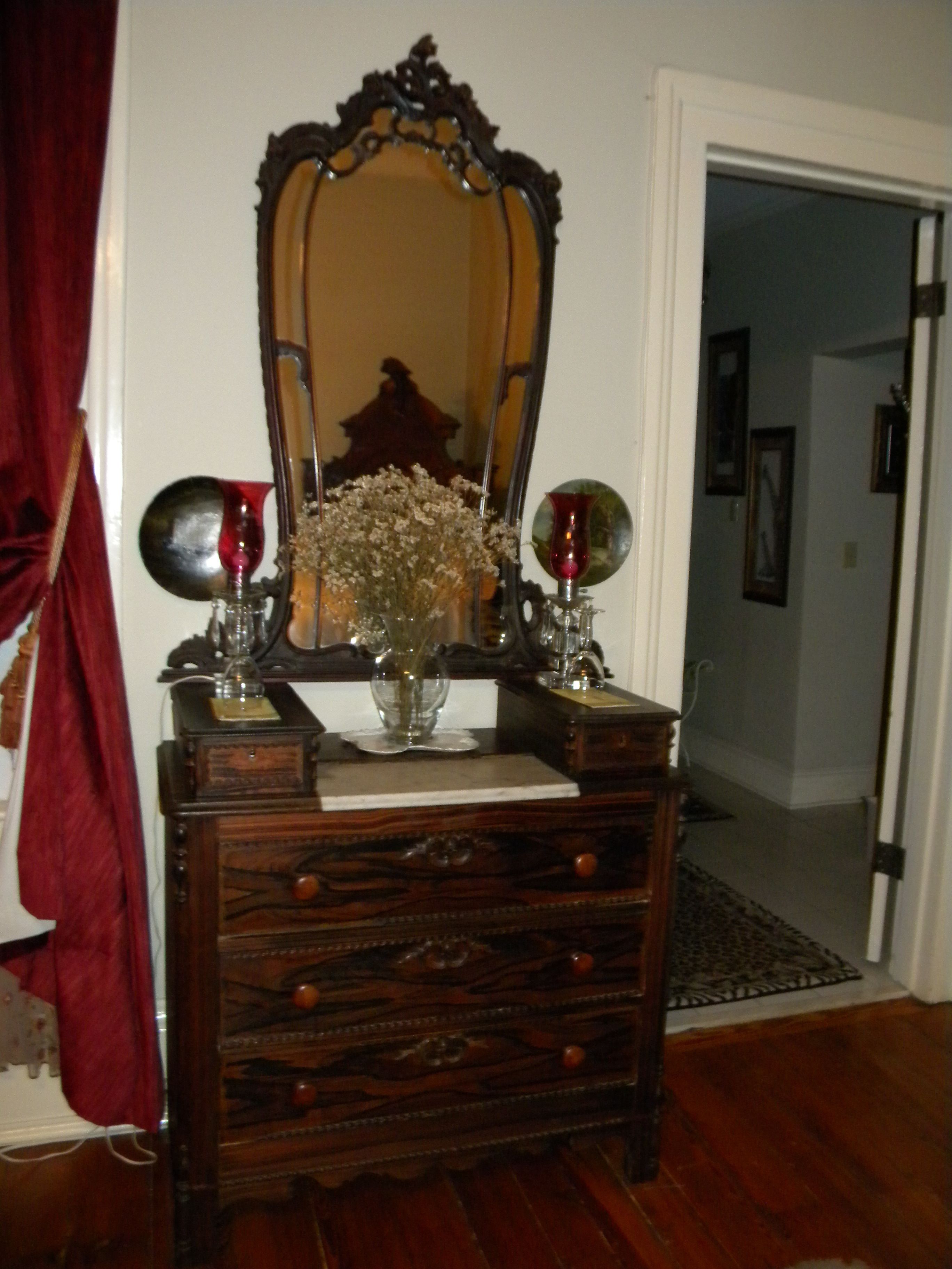 A wooden dresser with a mirror and two decorative vases.