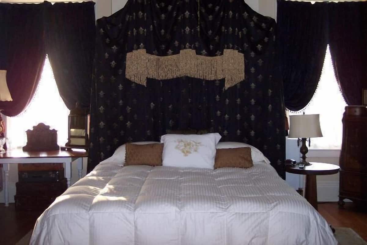 Ein Schlafzimmer mit einem Bett, einem Deckenventilator und Vorhängen.
