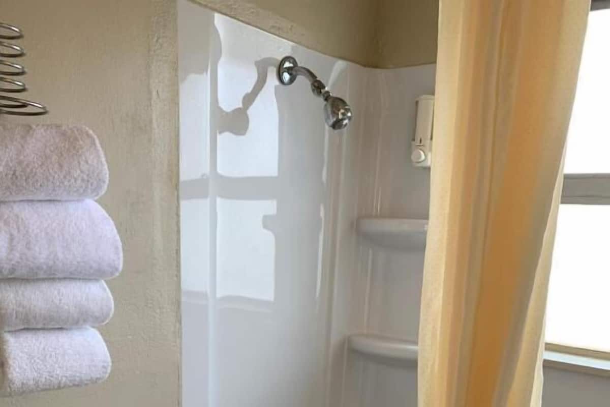 Ein Badezimmer mit Badewanne, Toilette und einem Handtuchhalter mit gefalteten Handtüchern.
