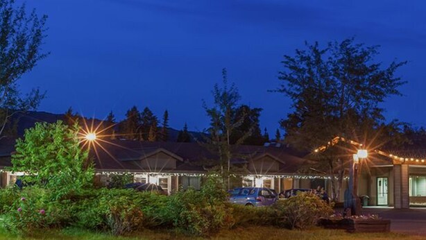 A lodge with a covered entrance, outdoor seating, and string lights. - Aspen Inn (Grand Marais)