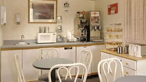 A small kitchenette with a microwave, toaster, and coffee maker. There is a table with chairs and a framed picture on the wall. - Aspen Inn (Grand Marais)