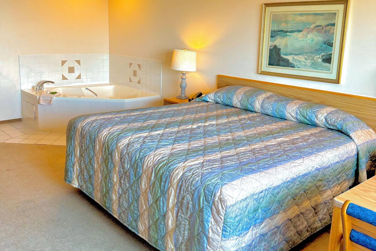 Una habitación de hotel con cama, baño y un cuadro en la pared.