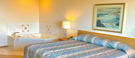A hotel room with a bed, a bathroom, and a painting on the wall.