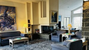Un salon moderne avec une cheminée, des sièges confortables et des œuvres d’art accrochées aux murs.