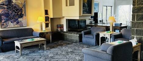 A modern living room with a fireplace, comfortable seating, and artwork on the walls.