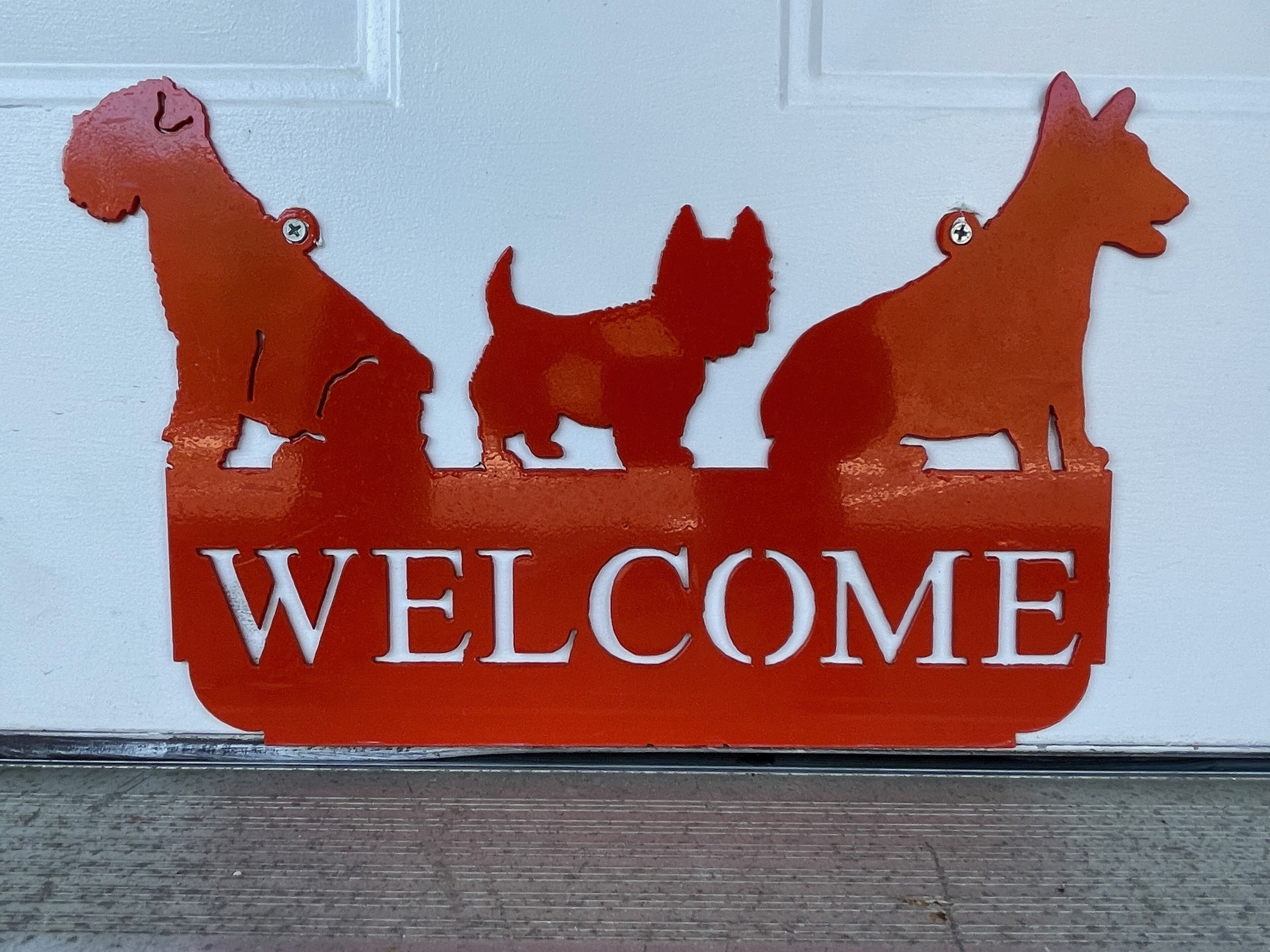 A welcome sign with silhouettes of three dogs.