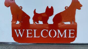 A welcome sign with silhouettes of three dogs.