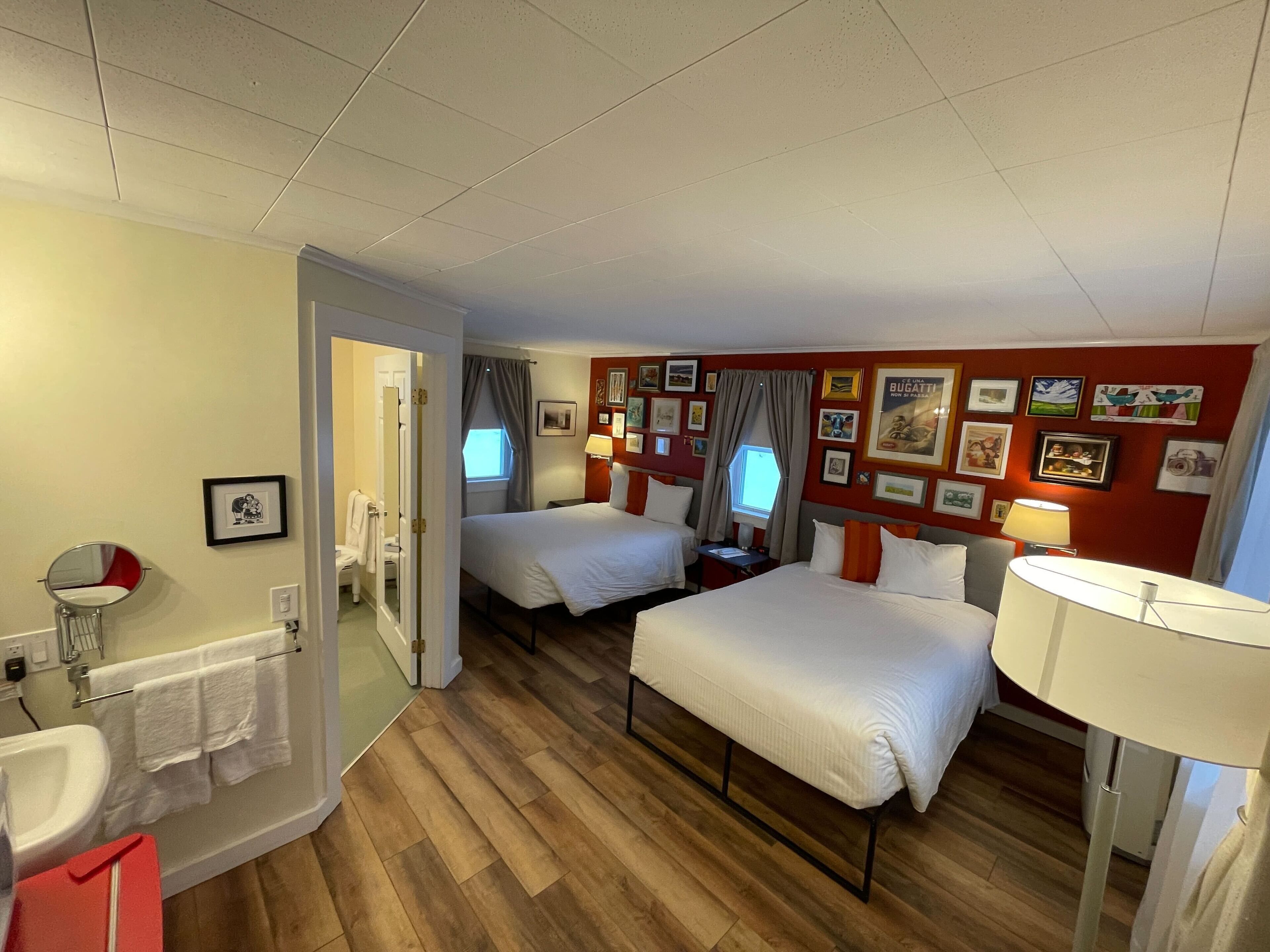 Habitación de hotel con dos camas, un baño y una pared decorada con fotografías.