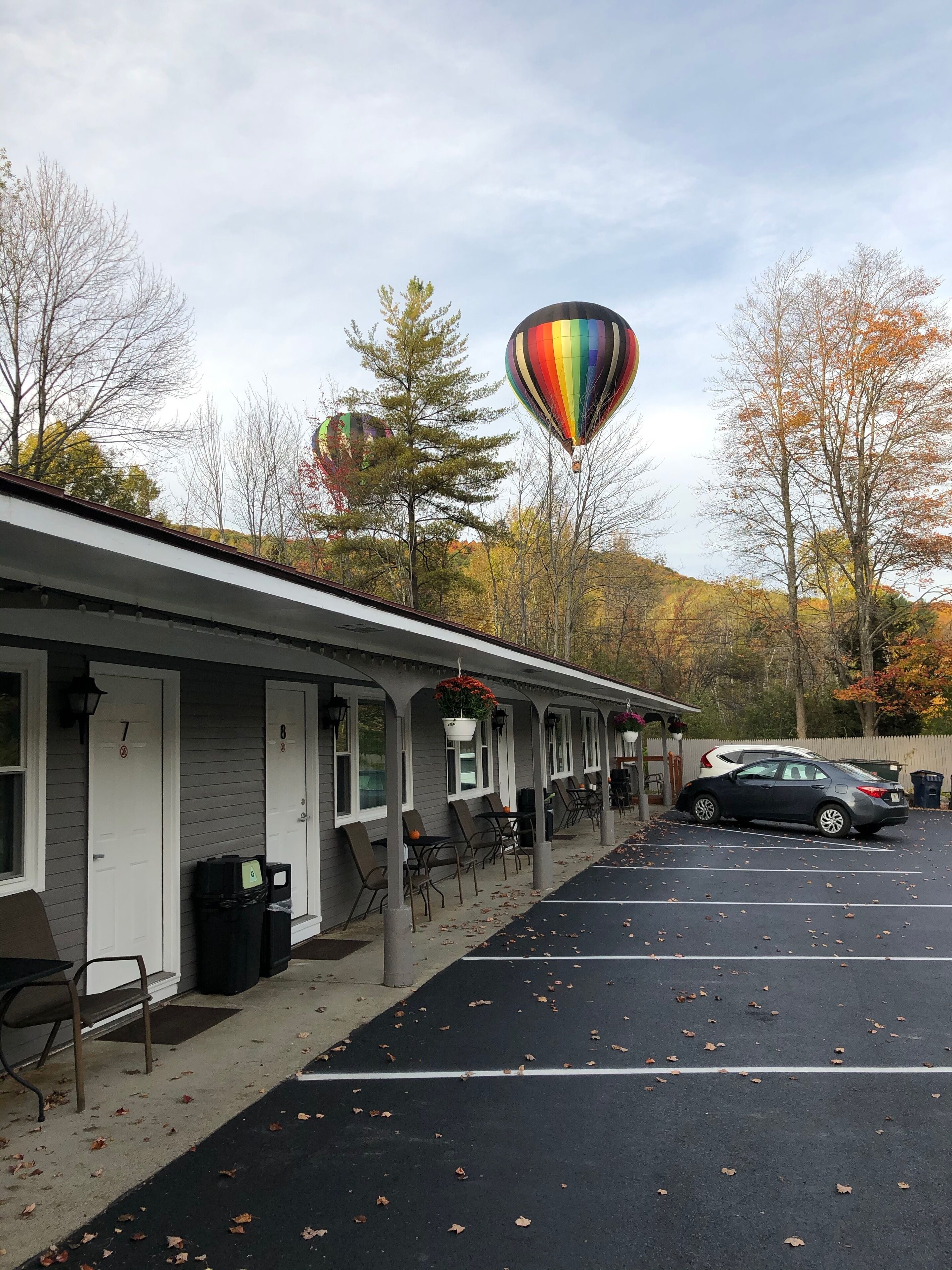A motel with numbered rooms, outdoor seating, and a parking lot.