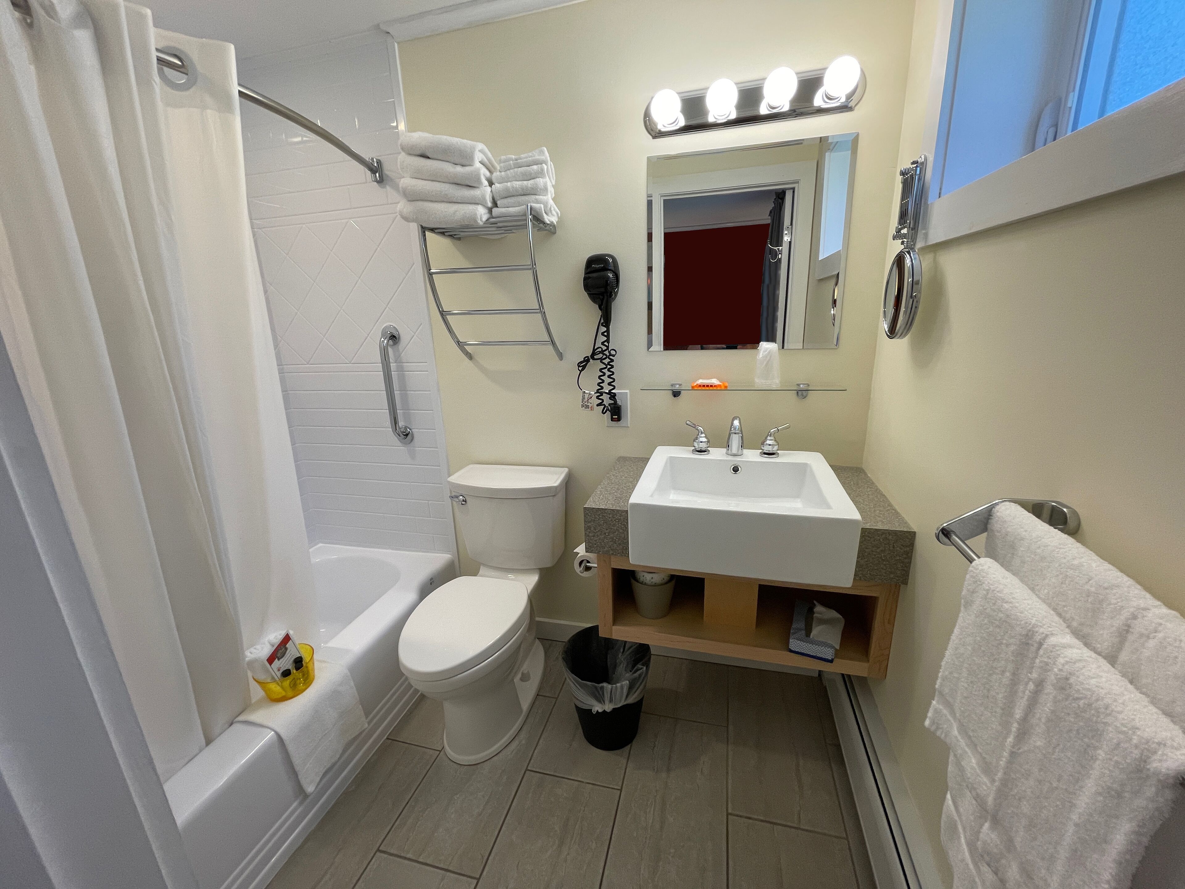 Een badkamer met een bad, toilet, wastafel en een spiegel met verlichting.