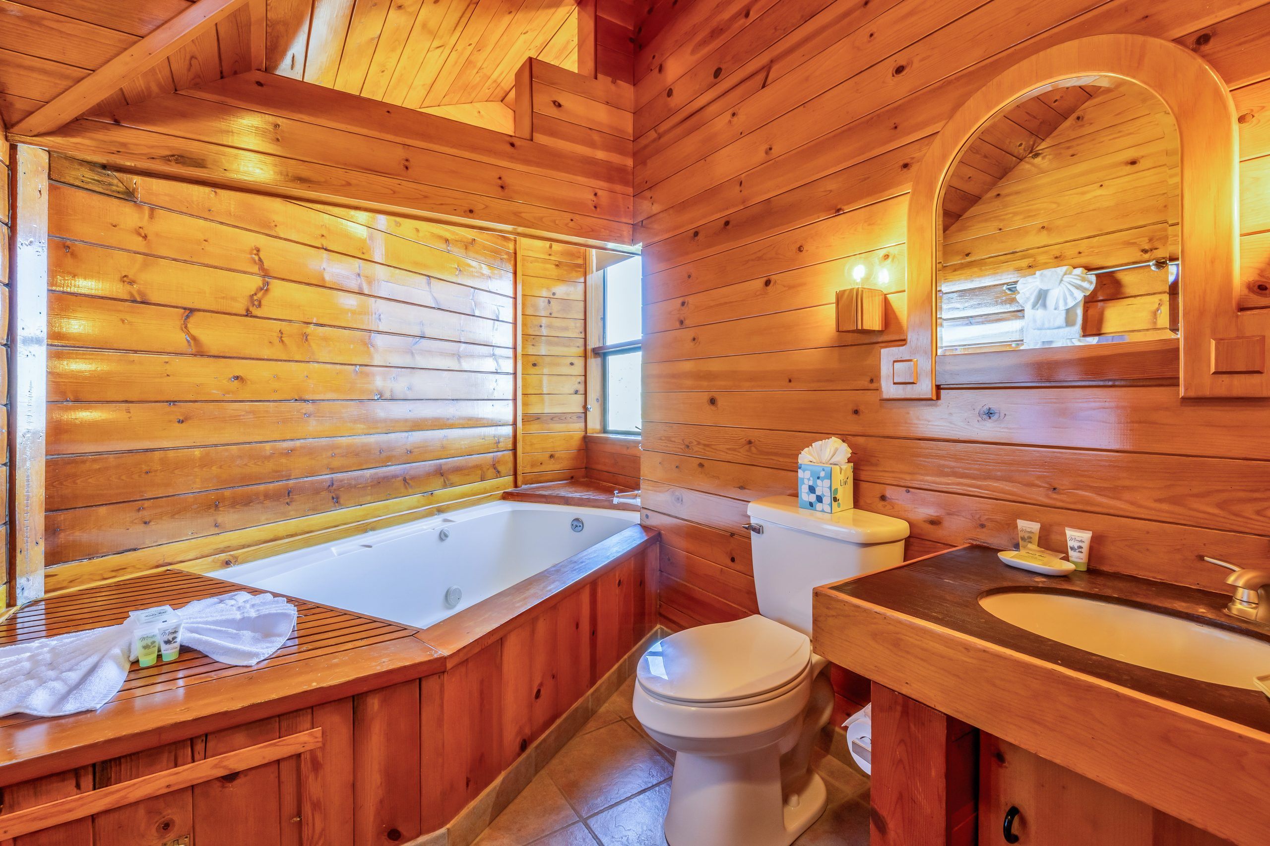 Une salle de bain rustique, avec une baignoire, des toilettes et un lavabo.