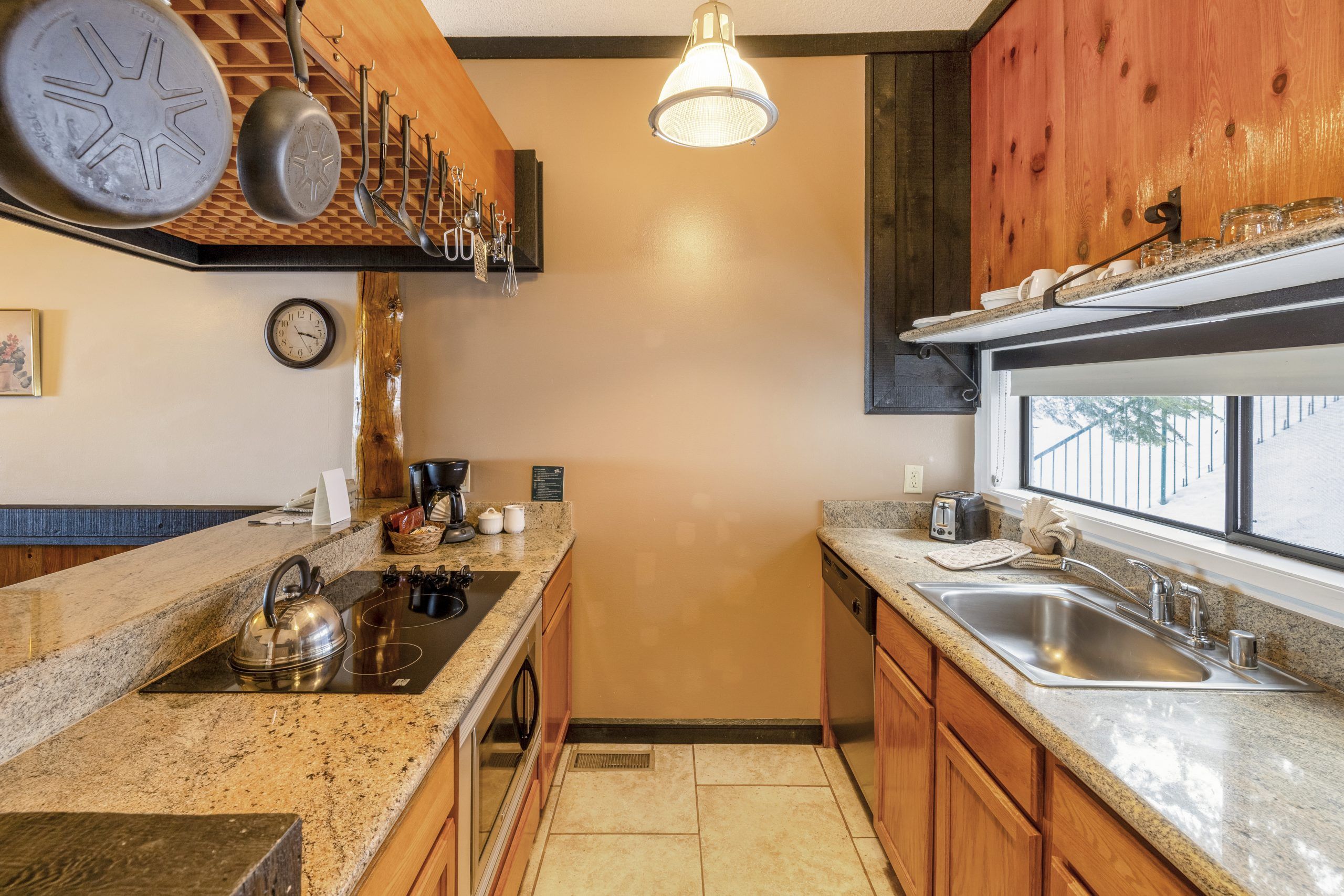 A compact kitchen with granite countertops, a stainless steel sink, a coffee maker, and a kettle.