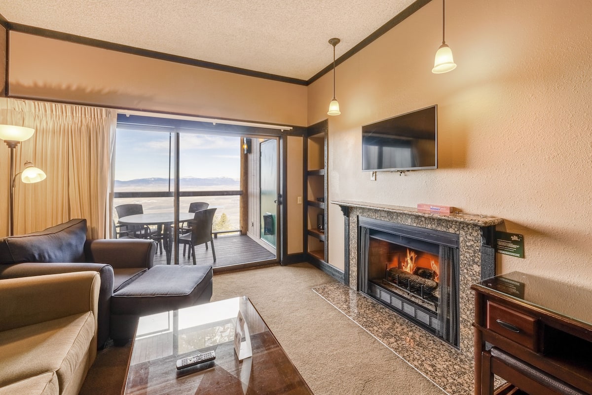 A modern living room with a fireplace, a sofa, a coffee table, and a TV mounted on the wall.
