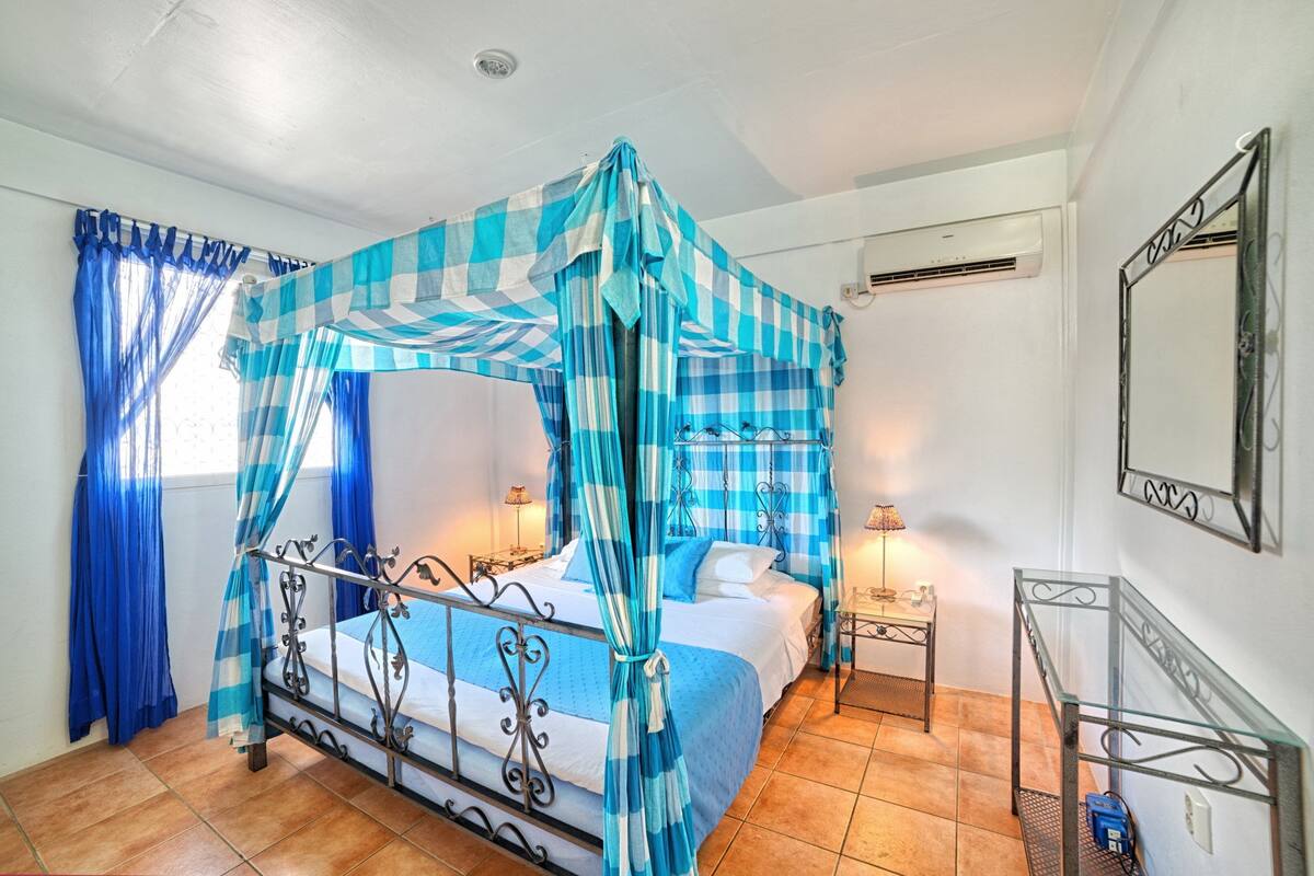 A room with a bed, a nightstand, a mirror, and a window with curtains.