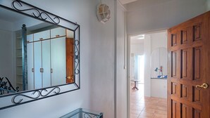 A hallway with a wooden door, a glass table, and a mirror on the wall. - Caribbean Sea View Holiday Apartments (Mero)