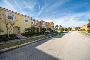A row of townhouses with a clear street in front, a well-maintained lawn, and a clear sky.