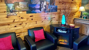 A cozy room with wooden paneling, a fireplace, and several framed pictures on the wall. - Mountain View Lodge & Cabins (Rapid City)
