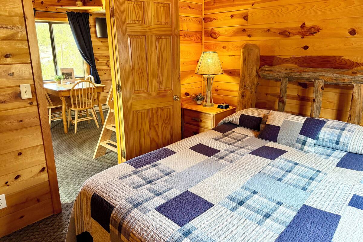 Une pièce dans un chalet en bois, comprenant un lit, un bureau et une chaise.