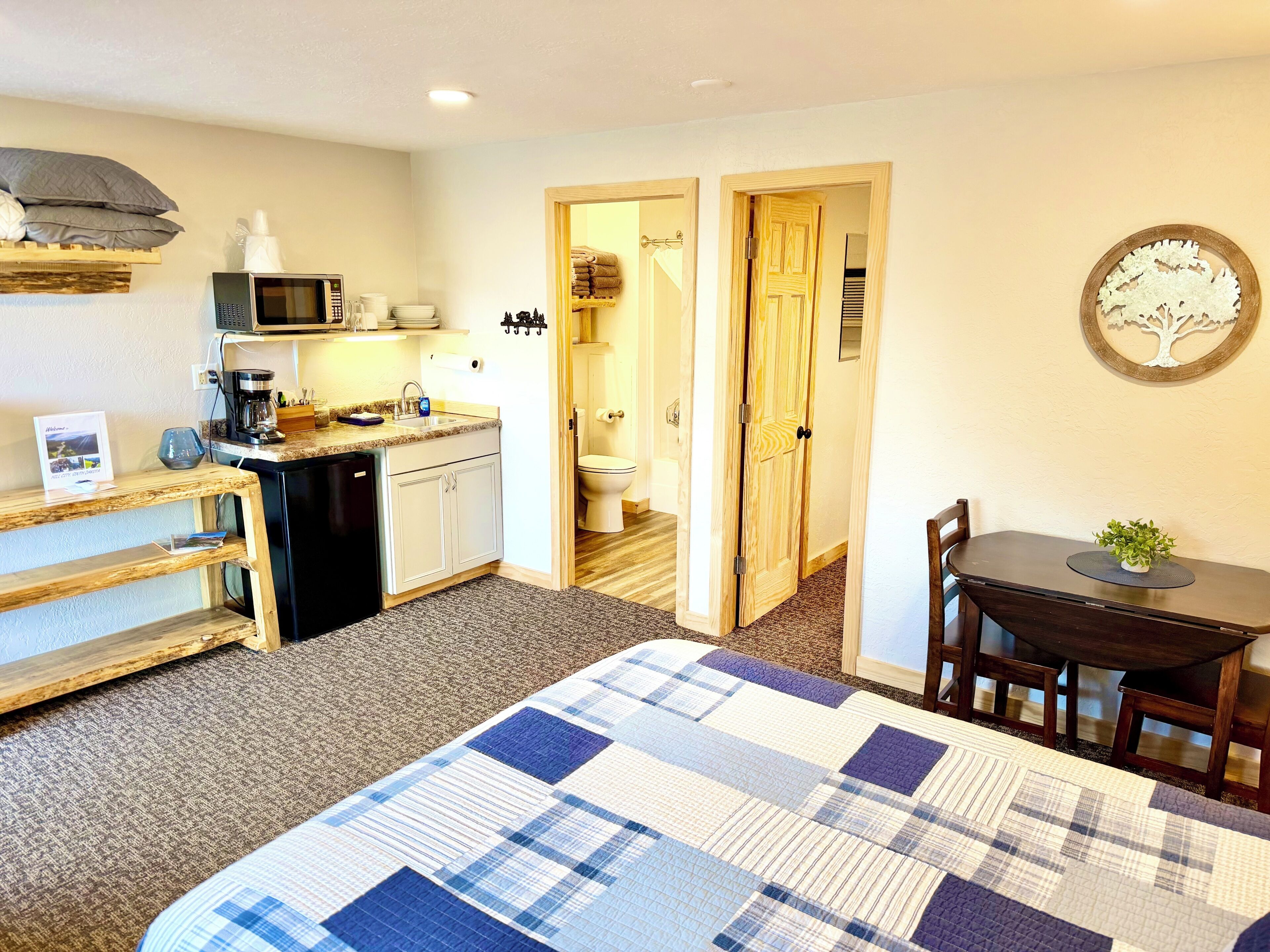 Een compacte kamer met een bed, een klein kitchenette, een eethoek en een badkamer.