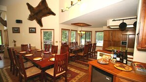 A spacious dining area with a wooden table and chairs, a kitchen with wooden cabinets, and a mounted animal hide on the wall. - Bar W Guest Ranch (Whitefish)