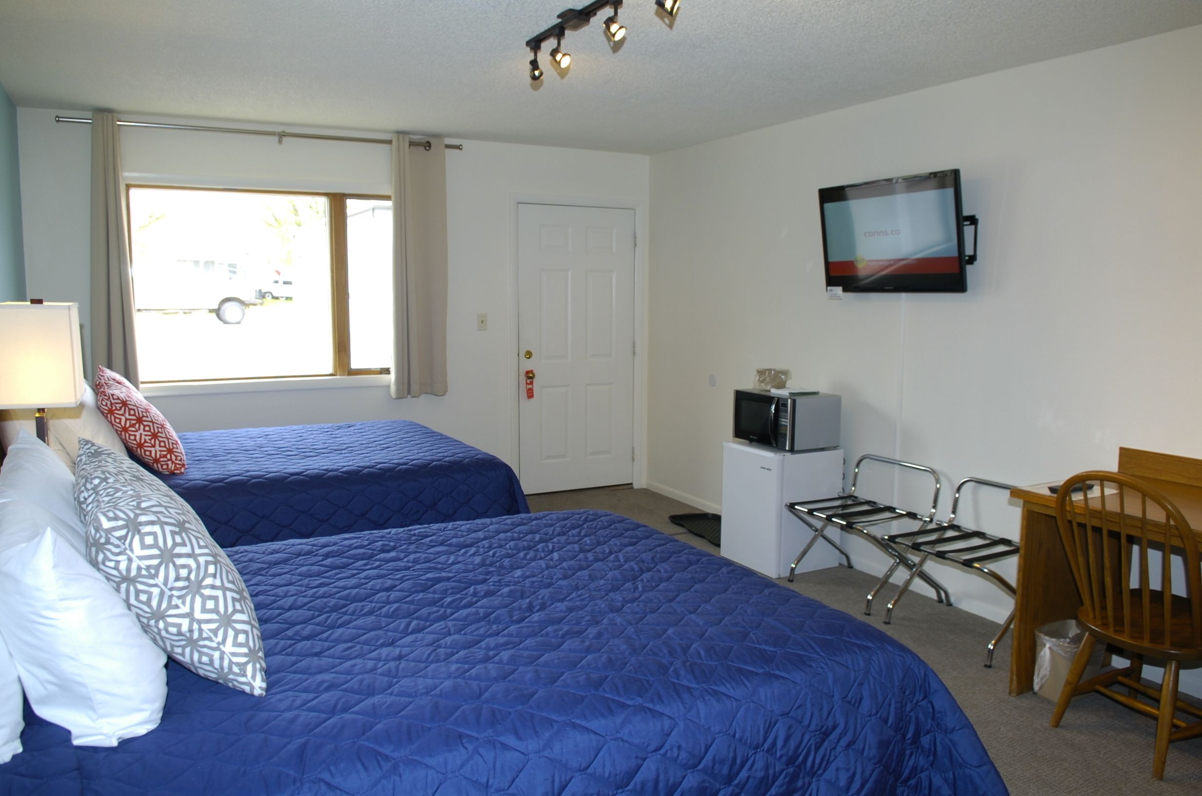 A room with two beds, a TV, a desk, and a chair.