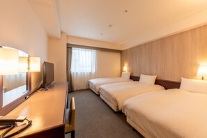Ein Hotelzimmer mit zwei Betten, einem Schreibtisch mit Stuhl, einem Fernseher und einer Lampe.