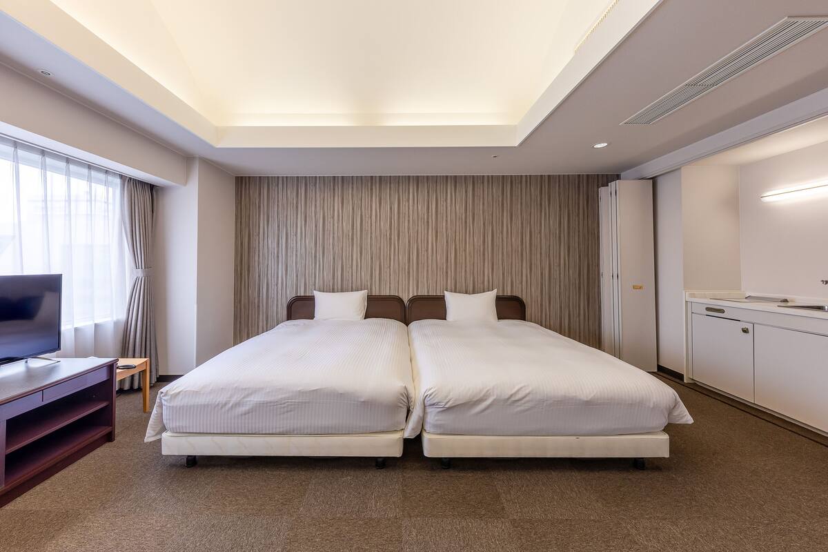 Une chambre d’hôtel avec un lit double, une télévision, une petite table et une armoire.