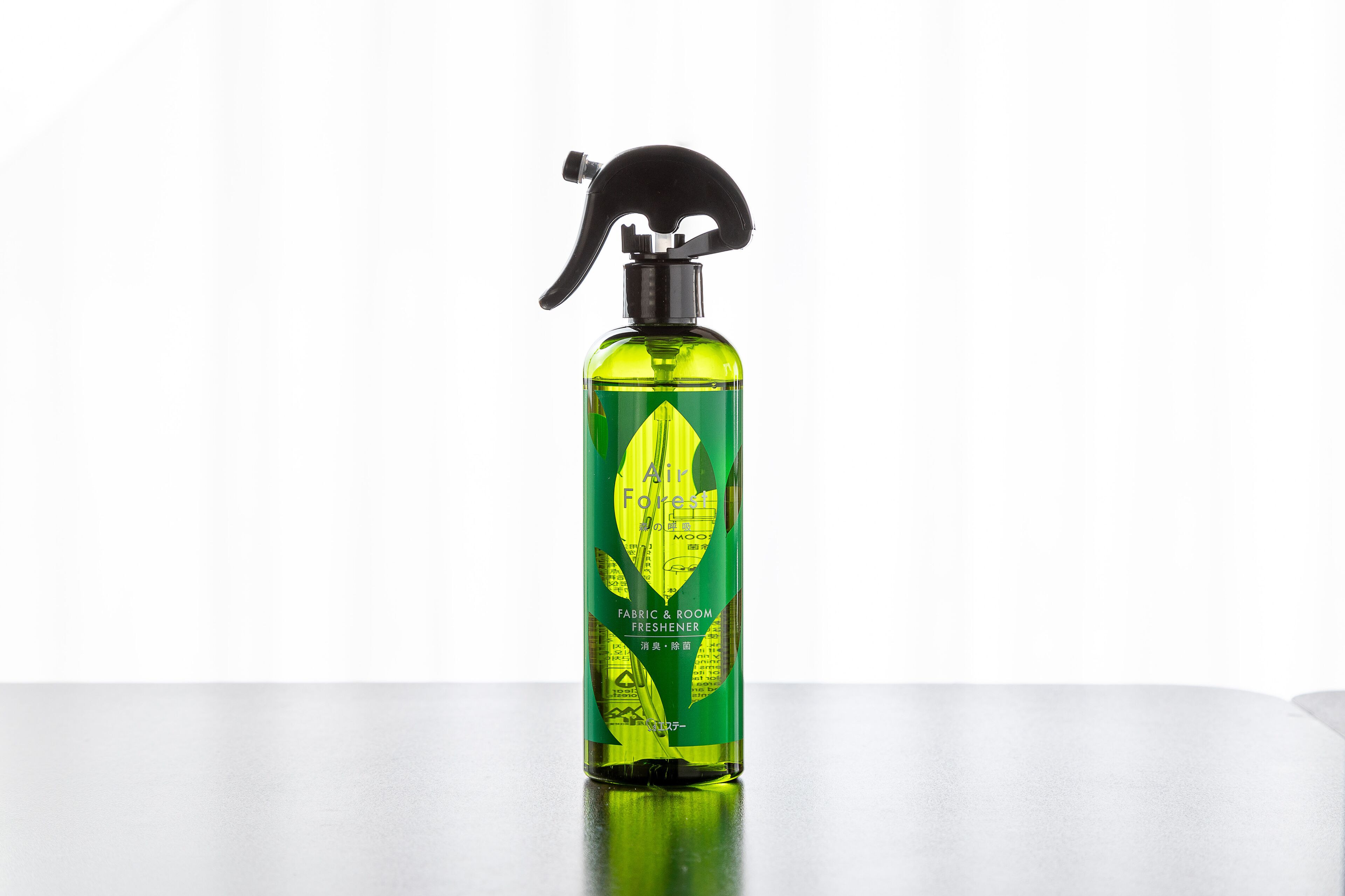 A bottle of air freshener on a reflective surface.