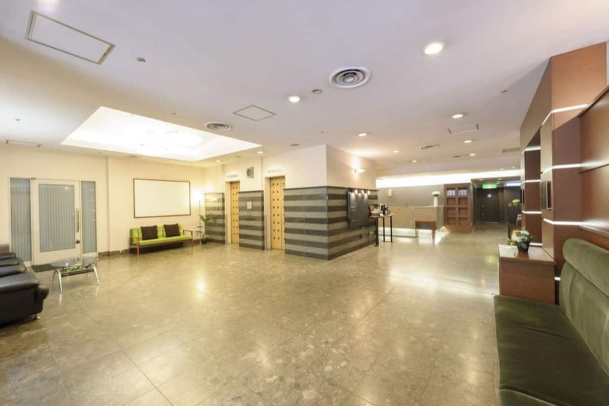 Un vestíbulo amplio con una recepción, zona de estar y una escalera.