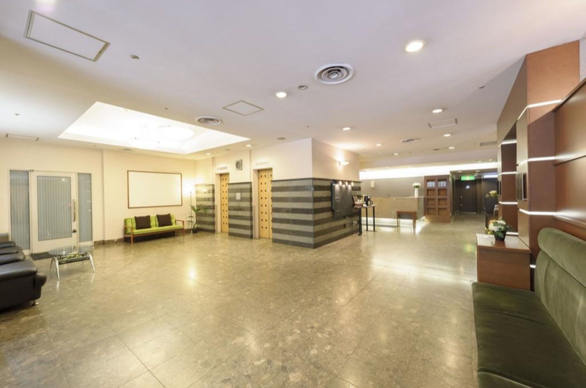 A spacious lobby with a reception desk, seating area, and a staircase.