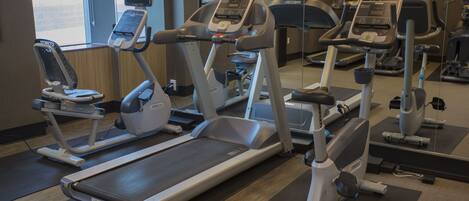 Un gimnasio con cintas de correr, elípticas y equipo de ejercicio.