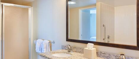 A bathroom with two sinks, a large mirror, and a shower.